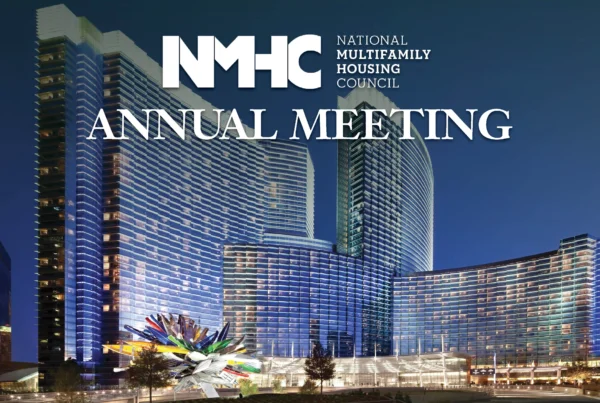 The image advertises the National Multifamily Housing Council (NMHC) Annual Meeting, with the organization's logo prominently displayed. The background features a vibrant night view of modern skyscrapers, illuminated with reflective lights, highlighting a large glass structure and a colorful artistic sculpture in the foreground.